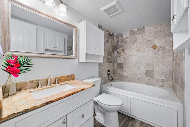 full bathroom with a textured ceiling, vanity, toilet, tiled shower / bath, and hardwood / wood-style flooring