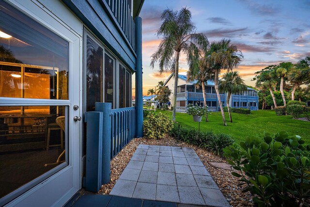 patio terrace at dusk featuring a yard