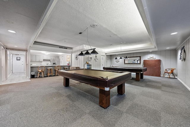 rec room with pool table, a raised ceiling, carpet, bar, and a textured ceiling