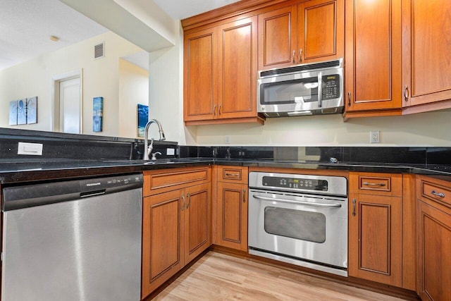 kitchen with light wood-type flooring, appliances with stainless steel finishes, and sink