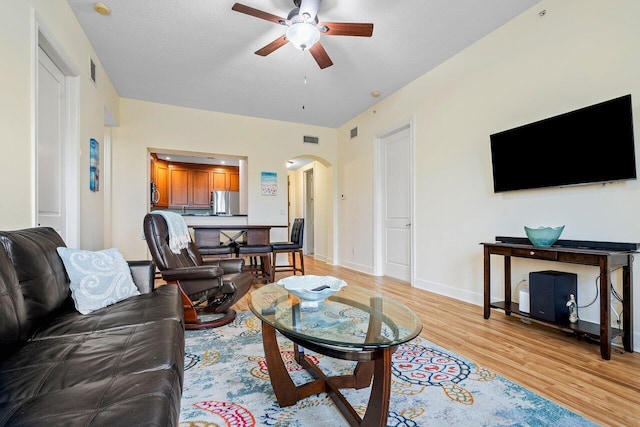 living room with light wood-type flooring, a textured ceiling, and ceiling fan