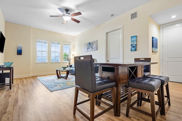 dining area featuring light wood-type flooring, a textured ceiling, and ceiling fan