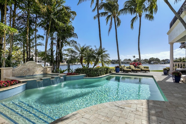 outdoor pool with a water view, a patio area, and an in ground hot tub