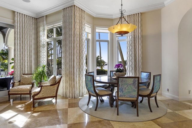 dining space with ornamental molding, arched walkways, and baseboards