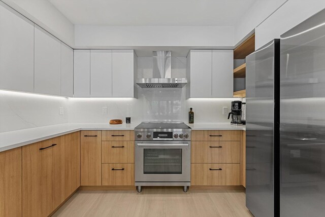 kitchen featuring backsplash, light brown cabinetry, stainless steel appliances, white cabinetry, and wall chimney exhaust hood