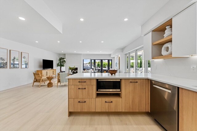 kitchen with light brown cabinetry, french doors, light wood-type flooring, stainless steel appliances, and kitchen peninsula