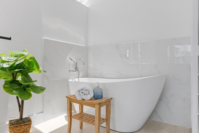 bathroom featuring tile walls and a bath