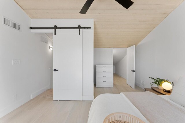 bedroom with wood ceiling, a barn door, ceiling fan, and light wood-type flooring