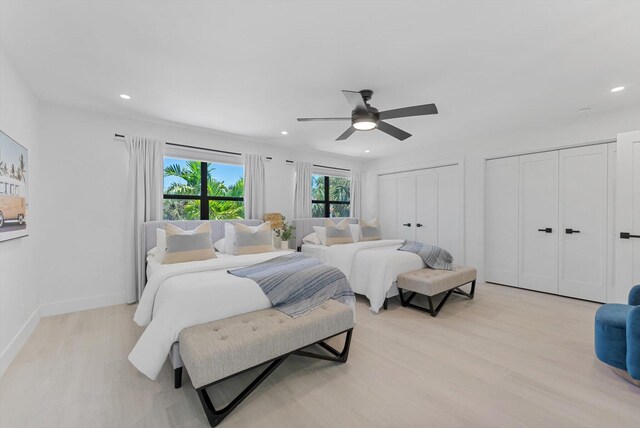 bedroom with two closets, ceiling fan, and light hardwood / wood-style floors