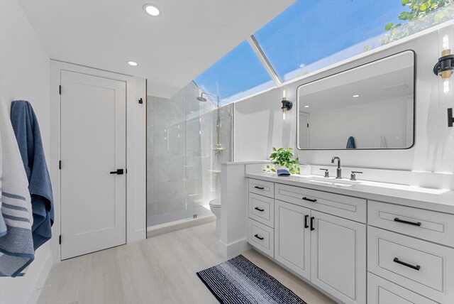 bathroom with a shower with door, vanity, toilet, and hardwood / wood-style floors