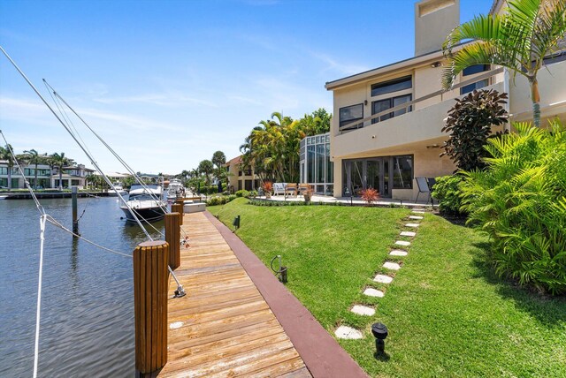 dock area with a water view, a yard, and a patio