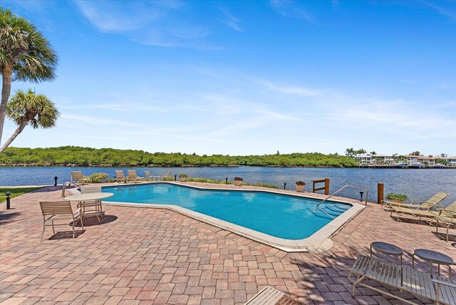 view of swimming pool featuring a water view and a patio