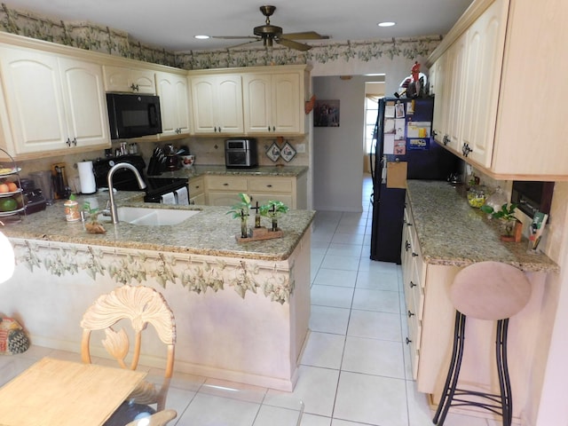 kitchen featuring light stone counters, black appliances, and kitchen peninsula