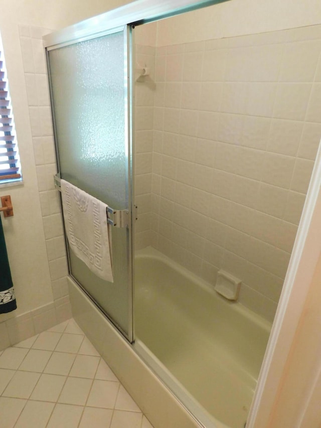 bathroom with shower / bath combination with glass door and tile patterned flooring