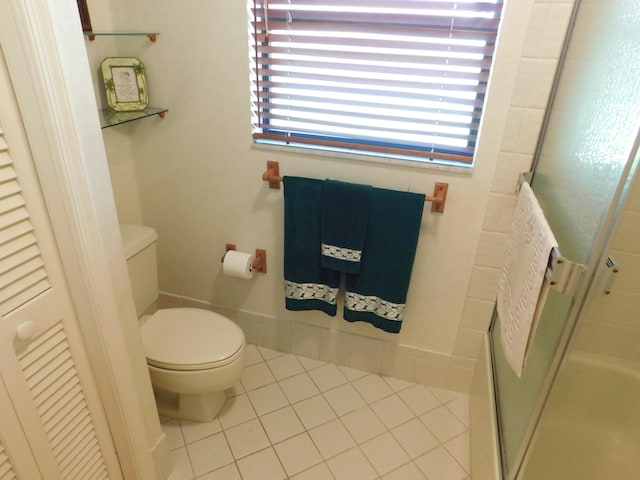 bathroom featuring a shower with shower door, toilet, and tile patterned flooring