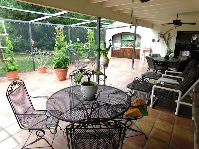 view of patio / terrace featuring ceiling fan and glass enclosure