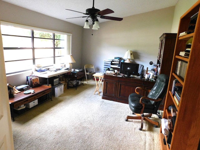 carpeted home office featuring a textured ceiling and ceiling fan