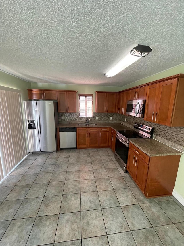 kitchen featuring tasteful backsplash, a textured ceiling, light tile patterned floors, sink, and appliances with stainless steel finishes