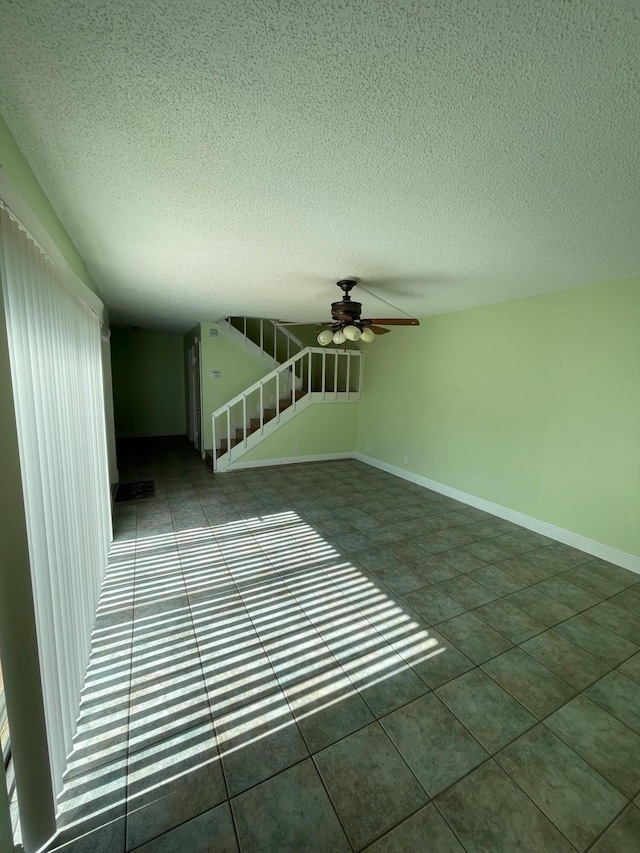 spare room featuring tile patterned flooring, ceiling fan, and a textured ceiling