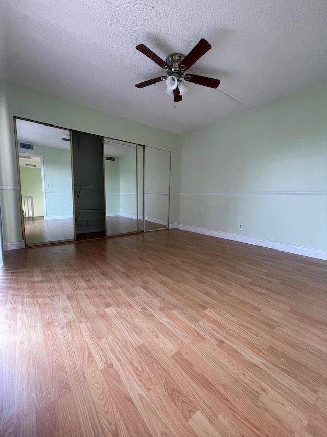 unfurnished bedroom with a textured ceiling, ceiling fan, a closet, and light hardwood / wood-style floors