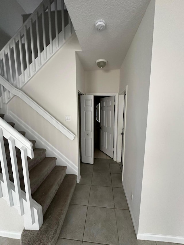 corridor featuring a textured ceiling and tile patterned flooring