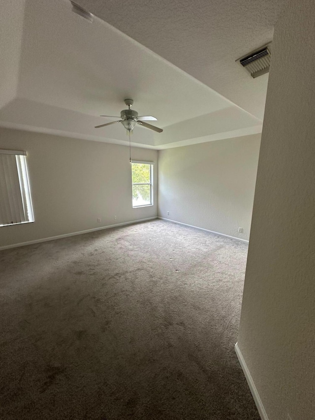 carpeted empty room with a tray ceiling and ceiling fan