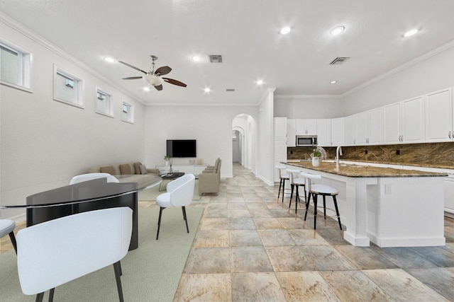 12520 NW 79th Mnr, Parkland, FL 33076 - living area featuring crown molding, arched walkways, ceiling fan, and visible vents