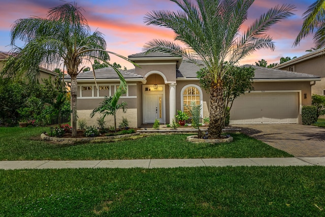 mediterranean / spanish-style home featuring a garage and a yard