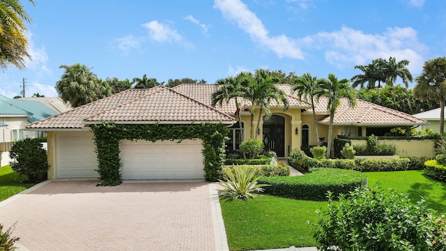 mediterranean / spanish-style home featuring a garage and a front yard