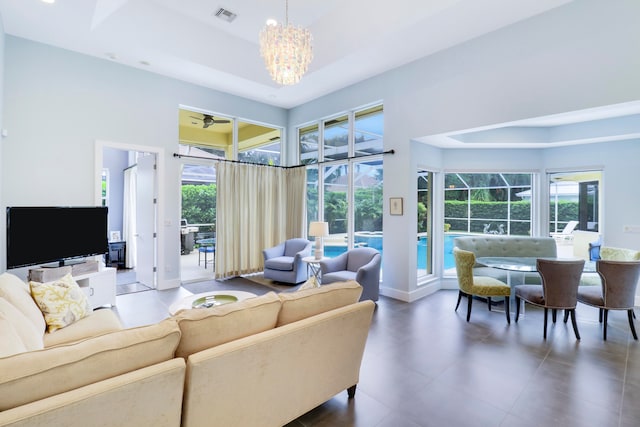 tiled living room featuring a raised ceiling and an inviting chandelier