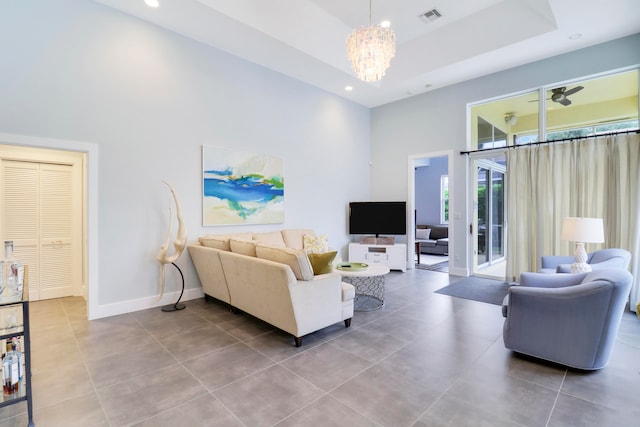 living room featuring a tray ceiling, a chandelier, a high ceiling, and tile patterned flooring