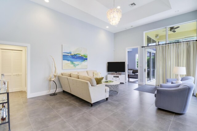 living room with a tray ceiling, tile patterned flooring, a chandelier, and a towering ceiling