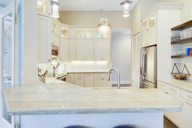 kitchen featuring light stone counters, decorative light fixtures, appliances with stainless steel finishes, and tasteful backsplash