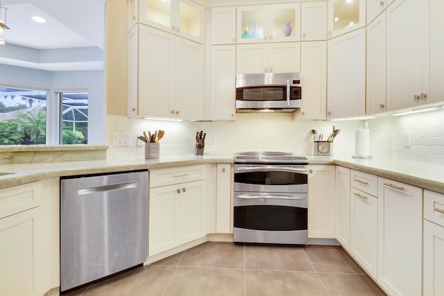 kitchen with light stone countertops, light tile patterned floors, stainless steel appliances, and tasteful backsplash