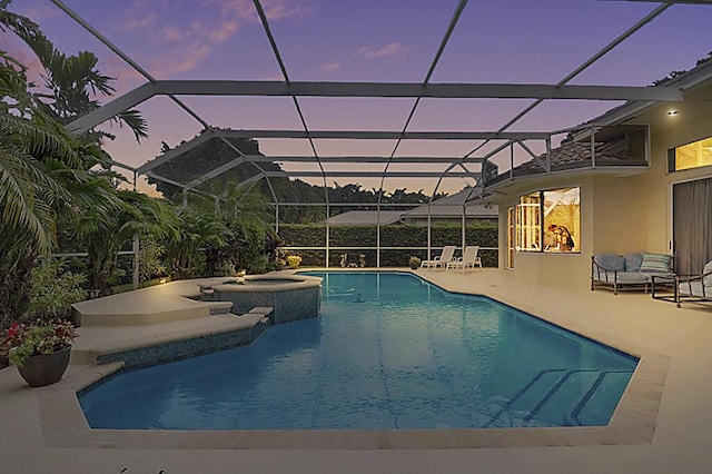 pool at dusk with an in ground hot tub, an outdoor pool, a patio area, and glass enclosure