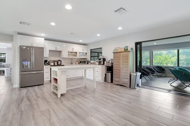 kitchen featuring white cabinetry, a kitchen breakfast bar, a center island, appliances with stainless steel finishes, and light hardwood / wood-style floors