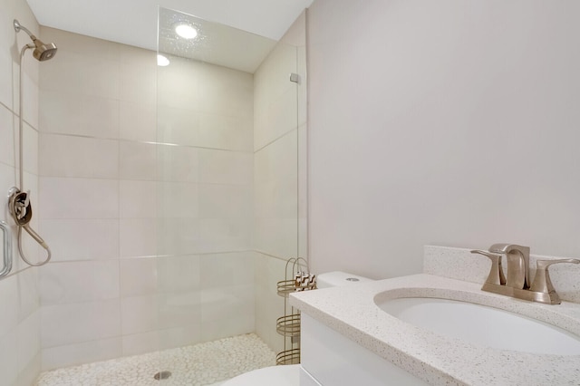 bathroom with vanity, toilet, and a tile shower