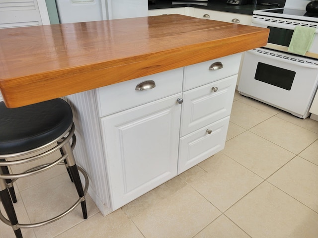 kitchen with range, white cabinetry, and light tile patterned flooring