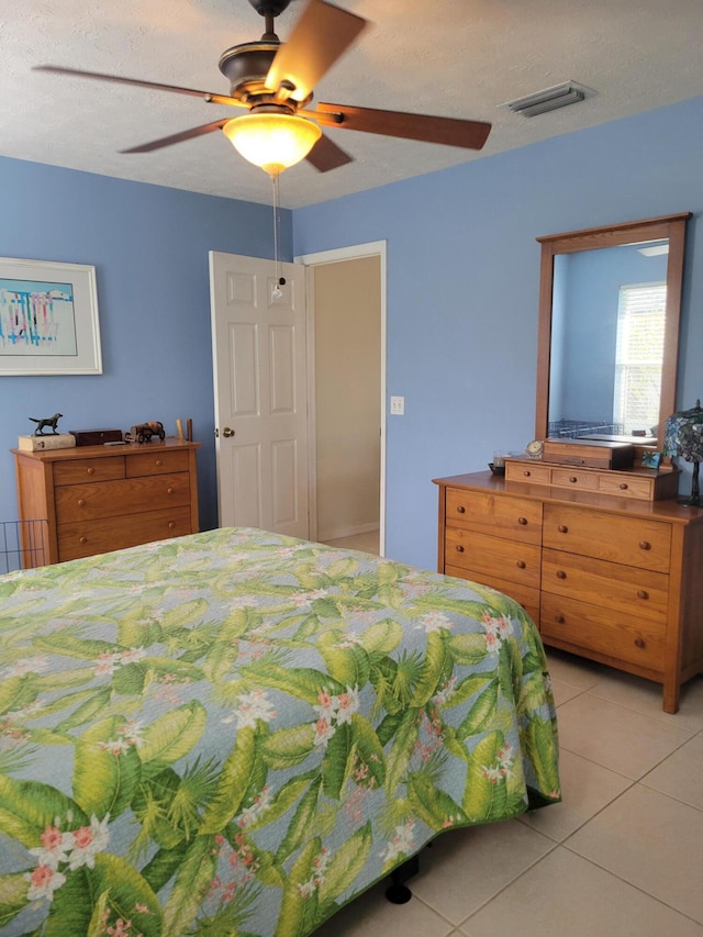 tiled bedroom with ceiling fan and a textured ceiling