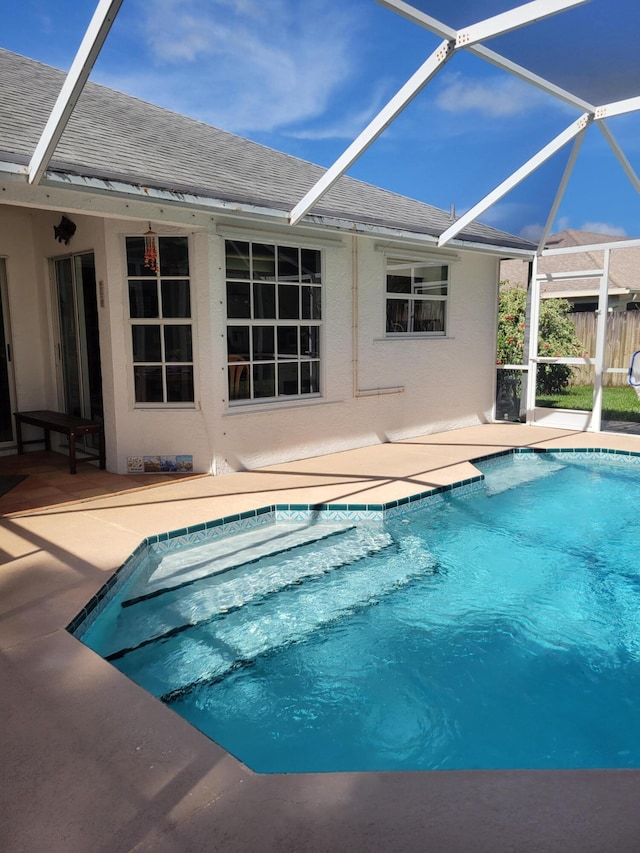 view of swimming pool with glass enclosure and a patio area