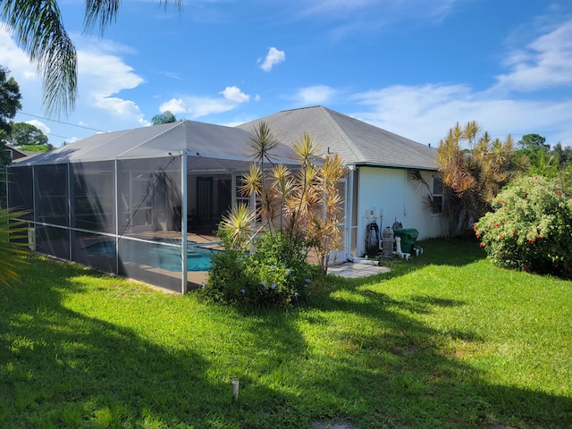 rear view of house with a yard and a lanai