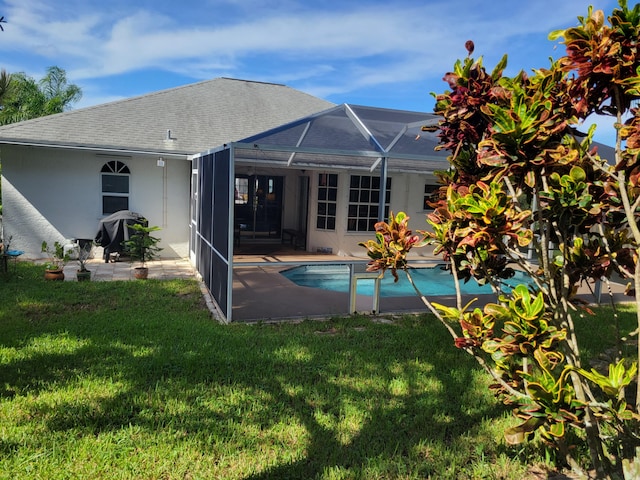 view of pool featuring glass enclosure and a lawn