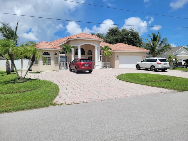 mediterranean / spanish house with a garage and a front lawn