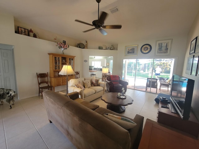 living room with ceiling fan, light tile patterned flooring, and a towering ceiling