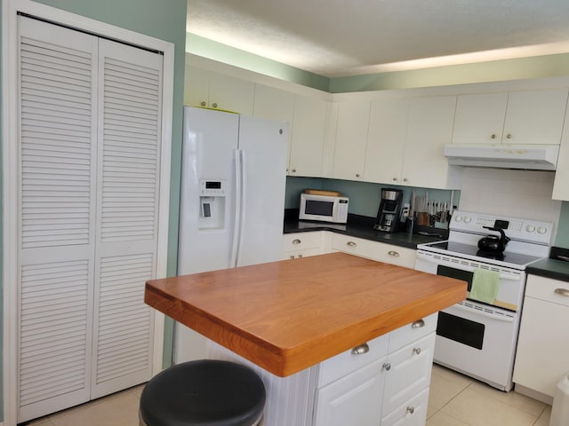 kitchen featuring a center island, white cabinets, white appliances, decorative backsplash, and light tile patterned floors