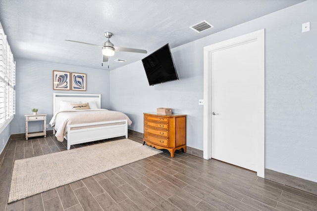 bedroom featuring ceiling fan, dark hardwood / wood-style flooring, and a textured ceiling