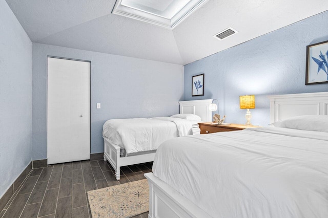 bedroom with lofted ceiling, dark hardwood / wood-style flooring, and a textured ceiling