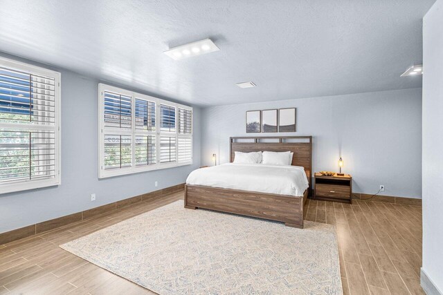 bedroom with a textured ceiling and light hardwood / wood-style floors