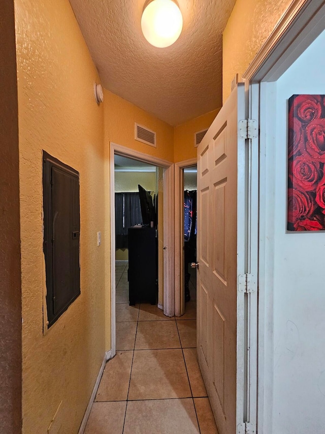 hallway with electric panel, light tile patterned flooring, and a textured ceiling