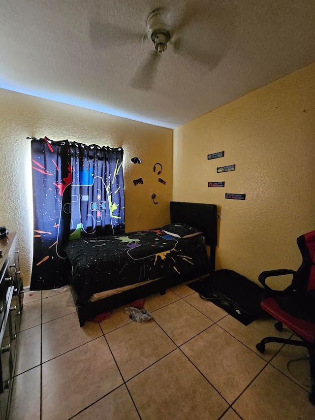 bedroom with a textured ceiling, ceiling fan, and tile patterned flooring